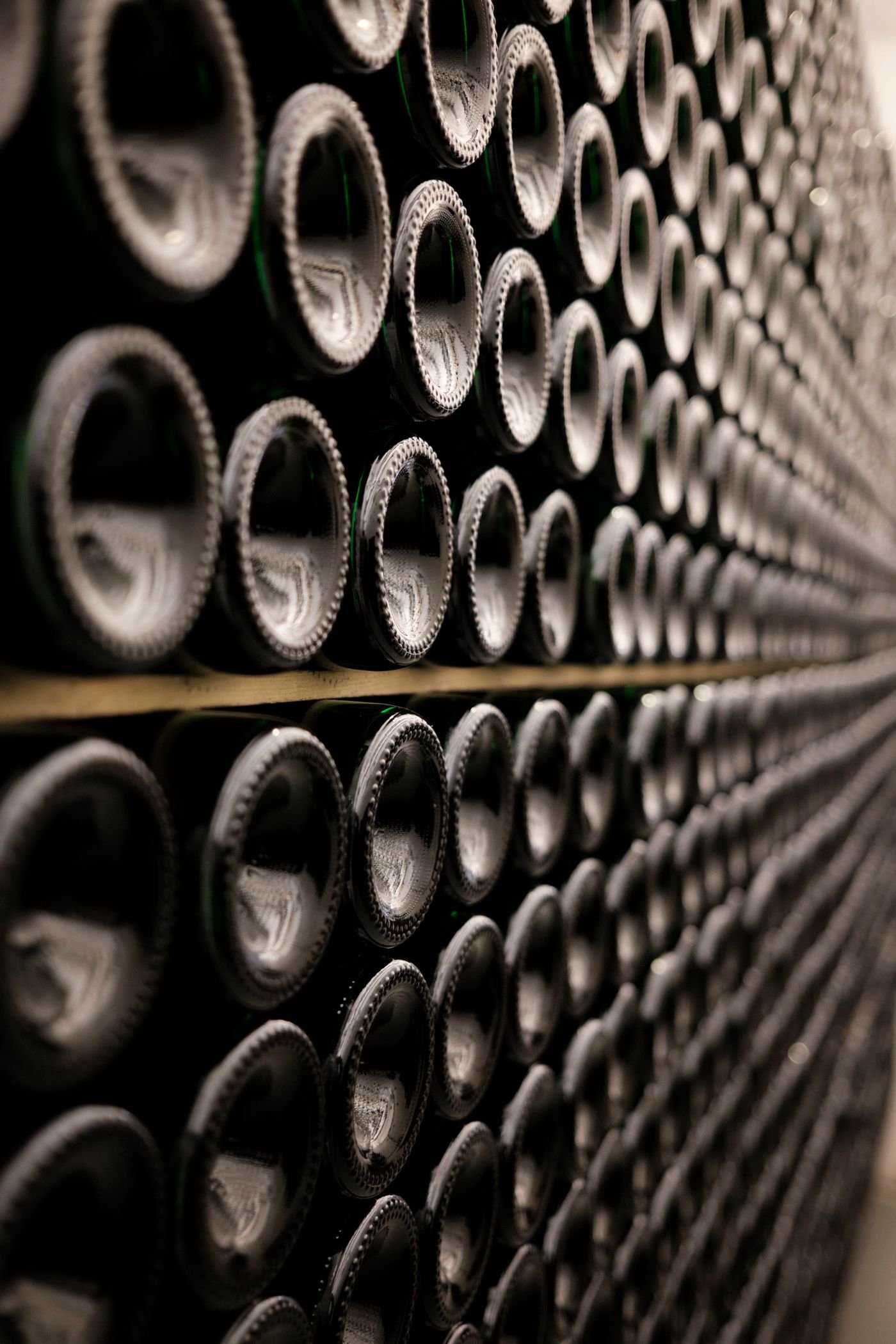 Rows of wine bottles resting in a dark cellar rack