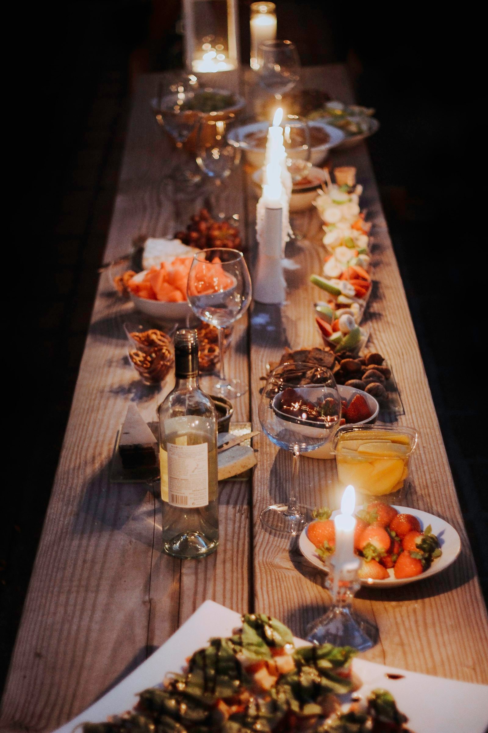 Candle-lit banquet table with wine glasses, bottles and shared plates for an event